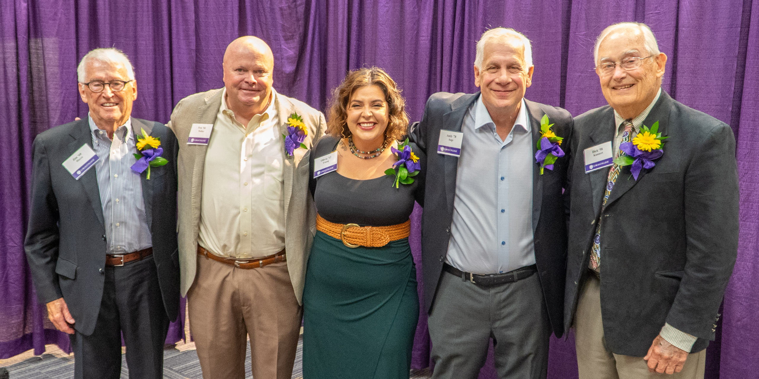 five alumni posing with award smiling at camera