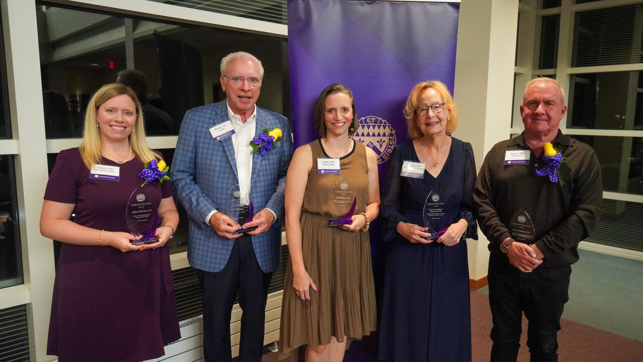 five individuals holding glass awards