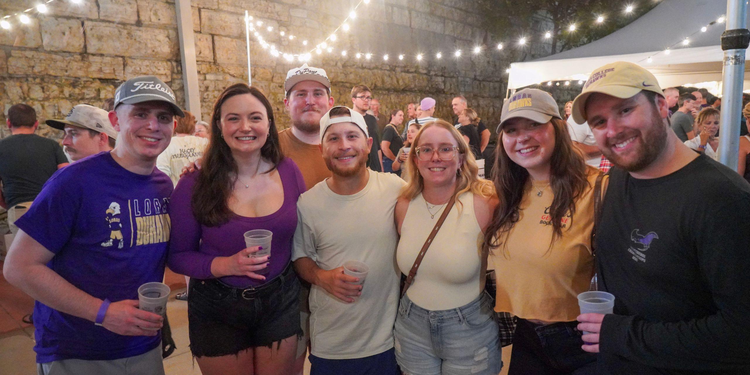Eight people smiling at event with cups in hand