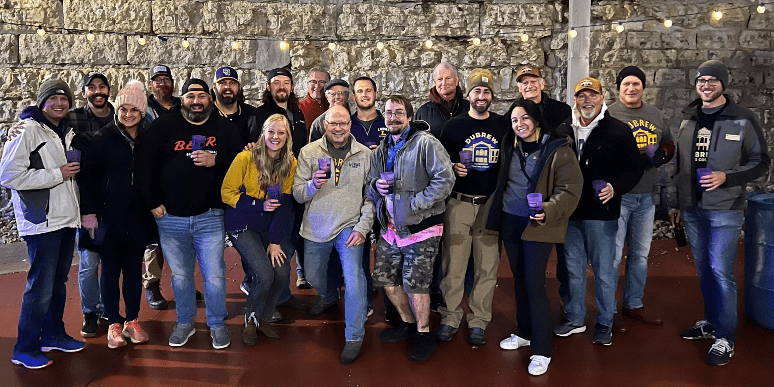 group of people posing by a rock wall at DuBrew 2024.