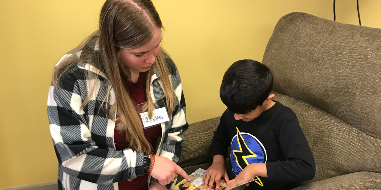 Sydney Davis ('25) reads to an immigrant child at The Lantern Center in Dubuque, IA