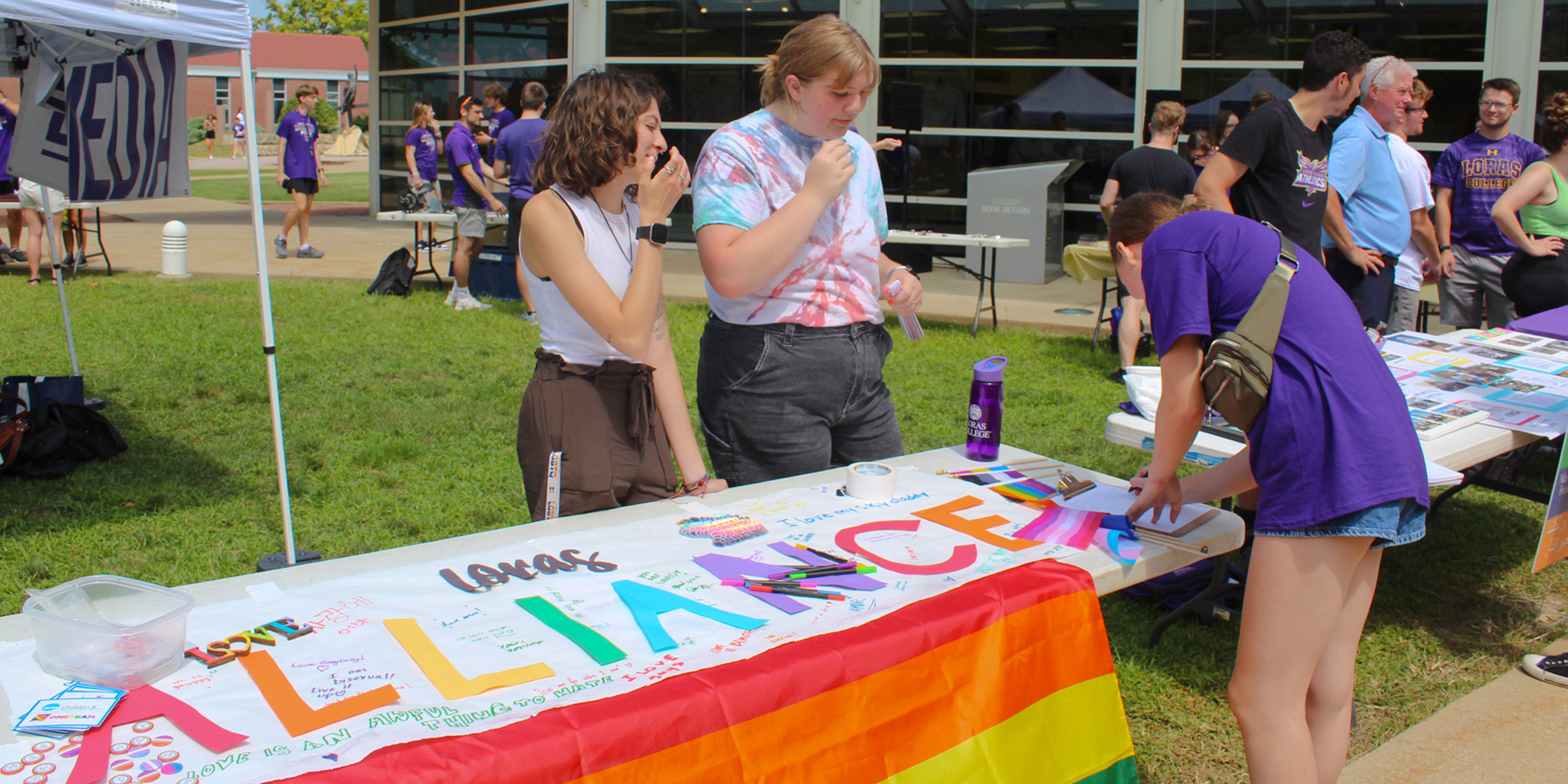 outside campus festival with students at table signing a banner