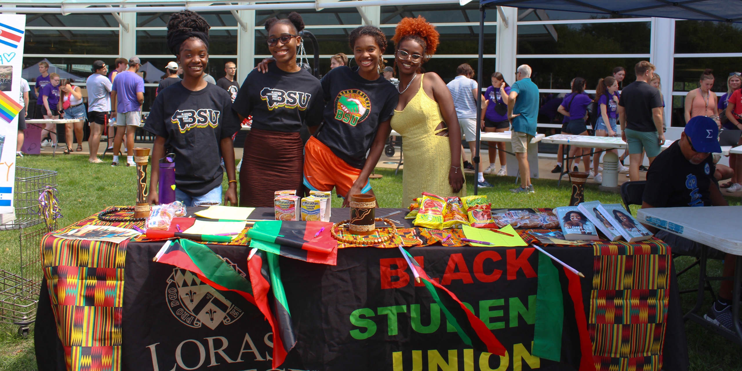 Four female students at campus fest outside in front of Black Student Union table