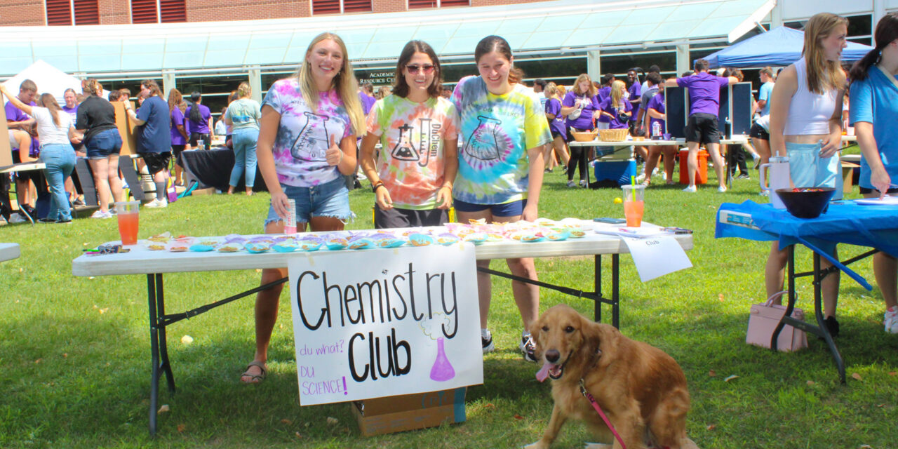Student in front of a Loras Campus Fest table promoting the Loras Chemistry Club