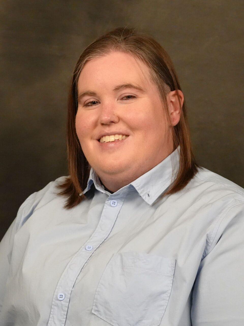 smiling individual in blue button up shirt