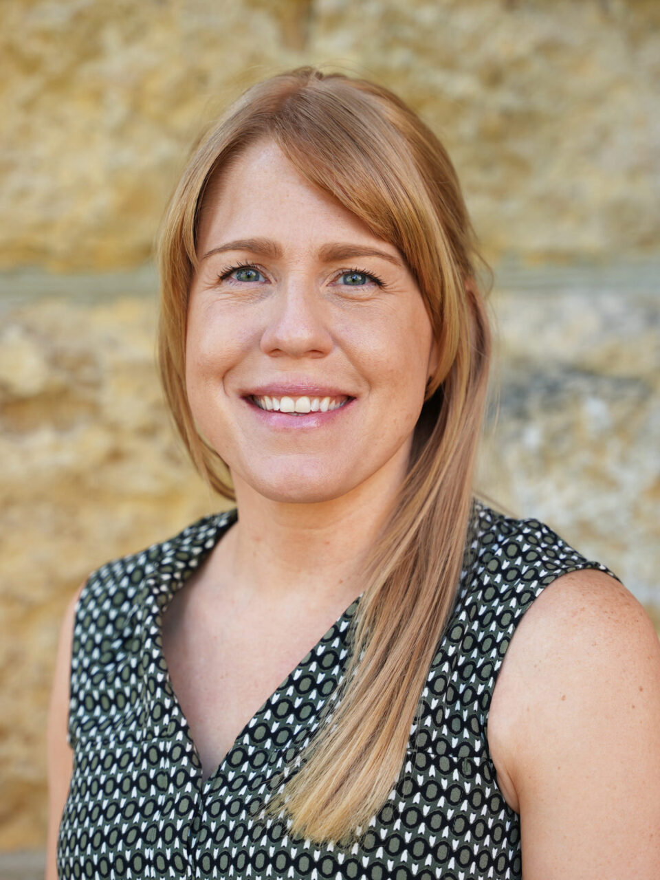 photo of Jill Specht standing in front of a brick wall at the Loras Rock Bowl Stadium