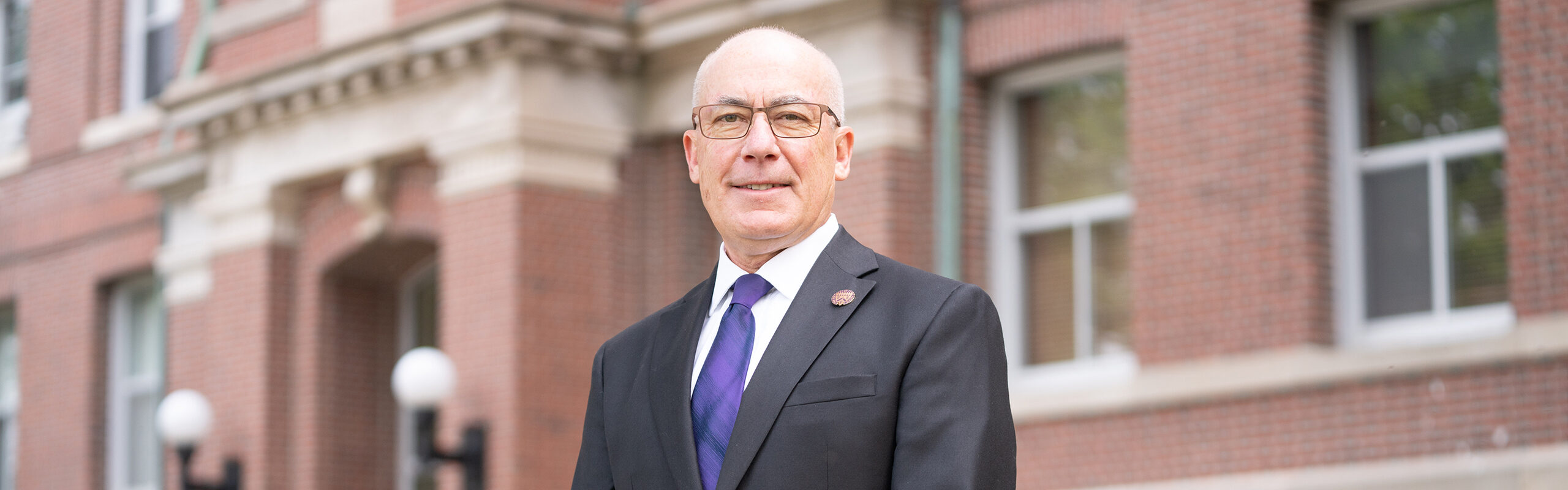 President Jim Collins standing on Keane Hall lawn outside