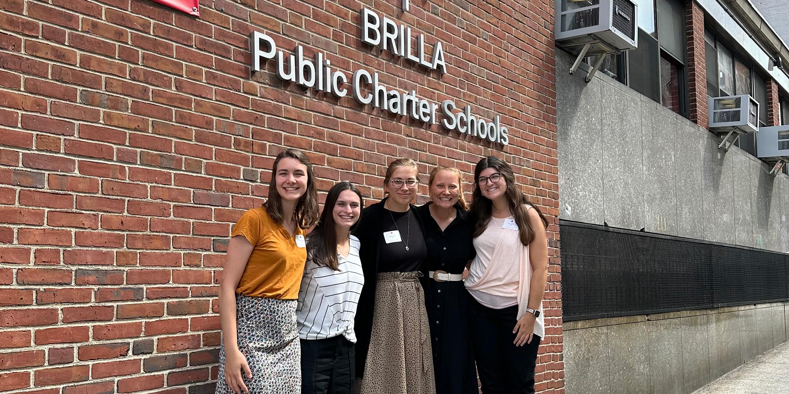 group of women smiling at camera in front of school