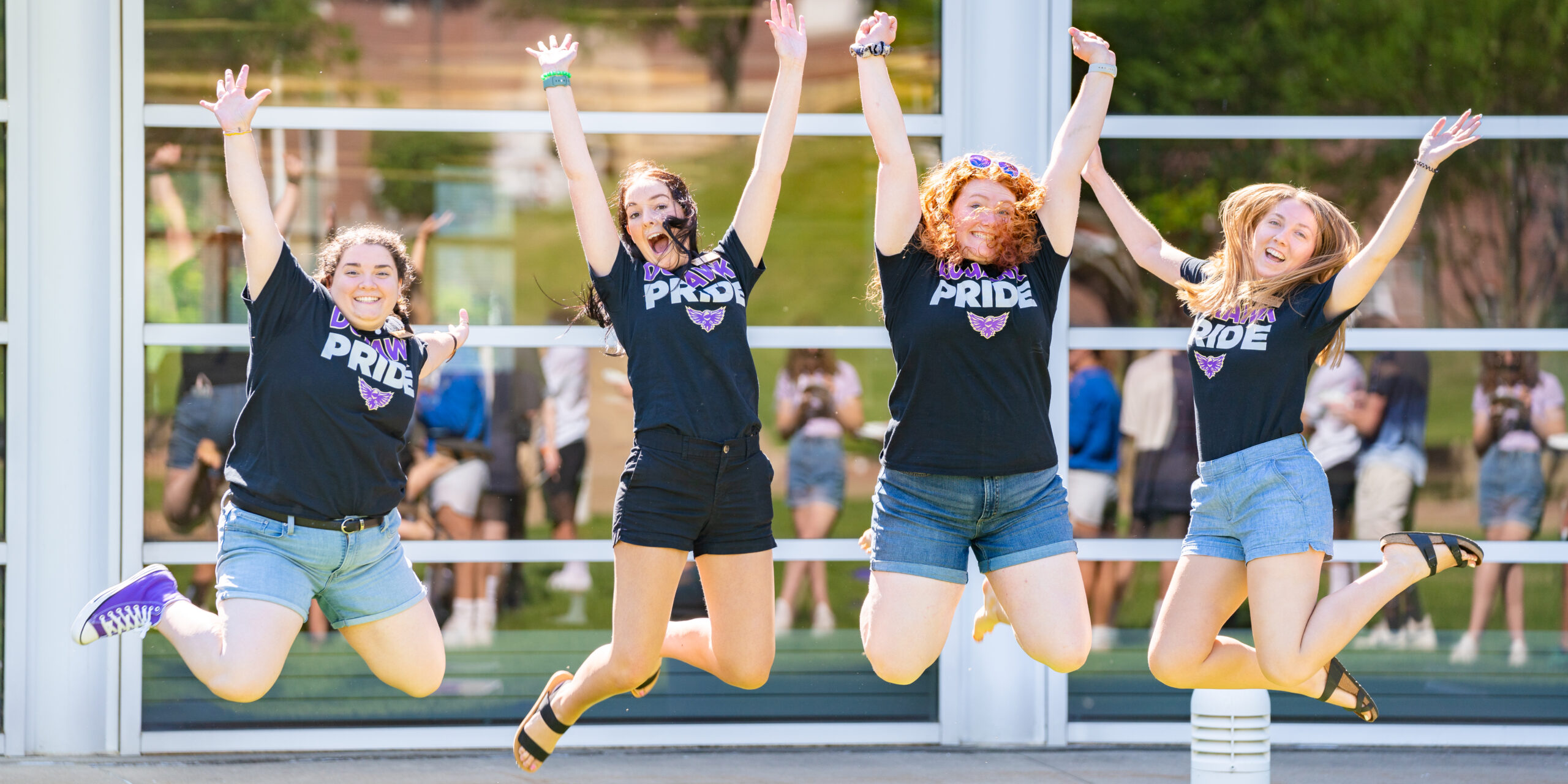 Loras students with loras Duhawk Pride t-shirts jumping in the air and smiling