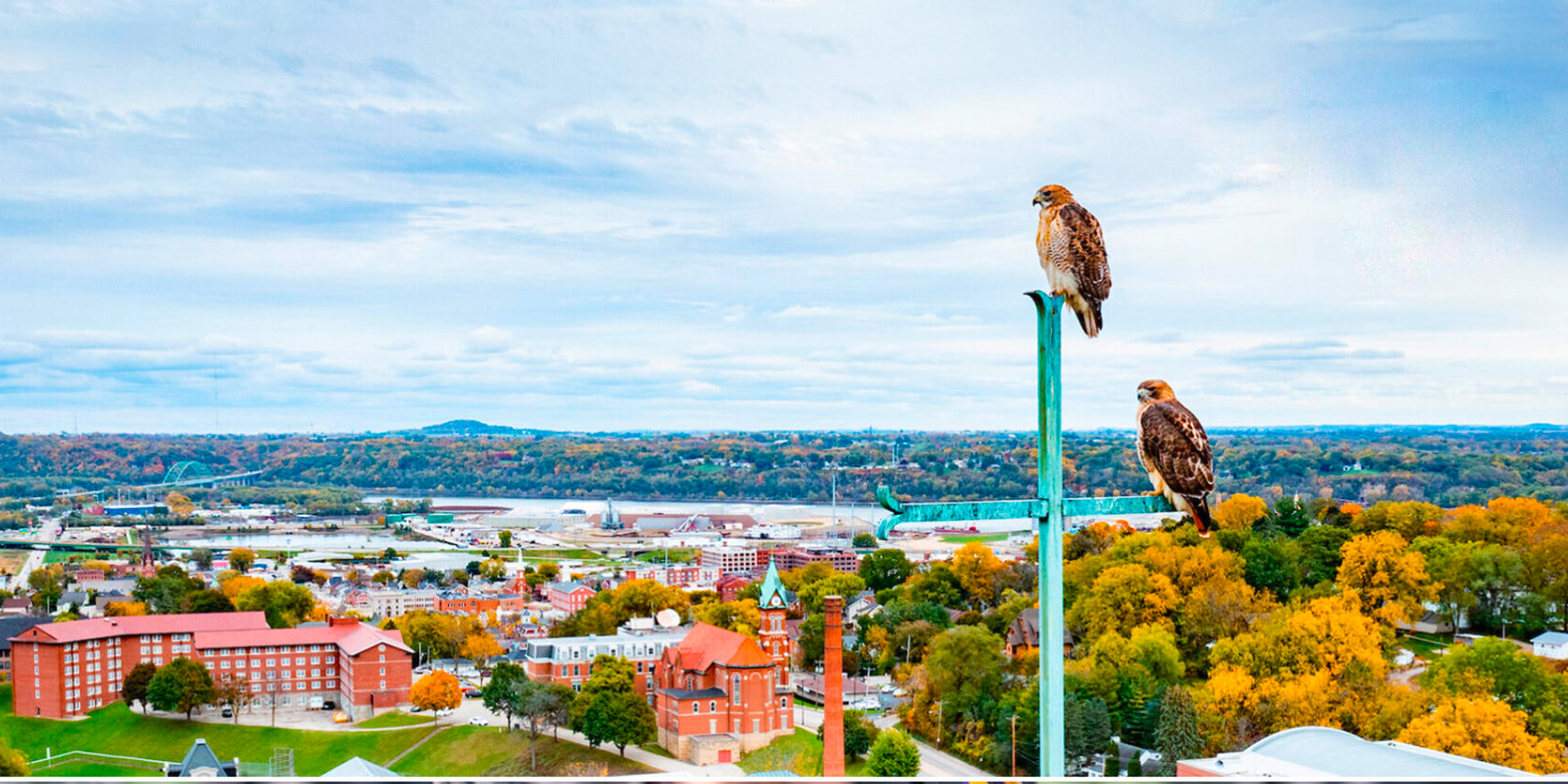 Two hawks perched on the highest point cross, protecting Loras College campus