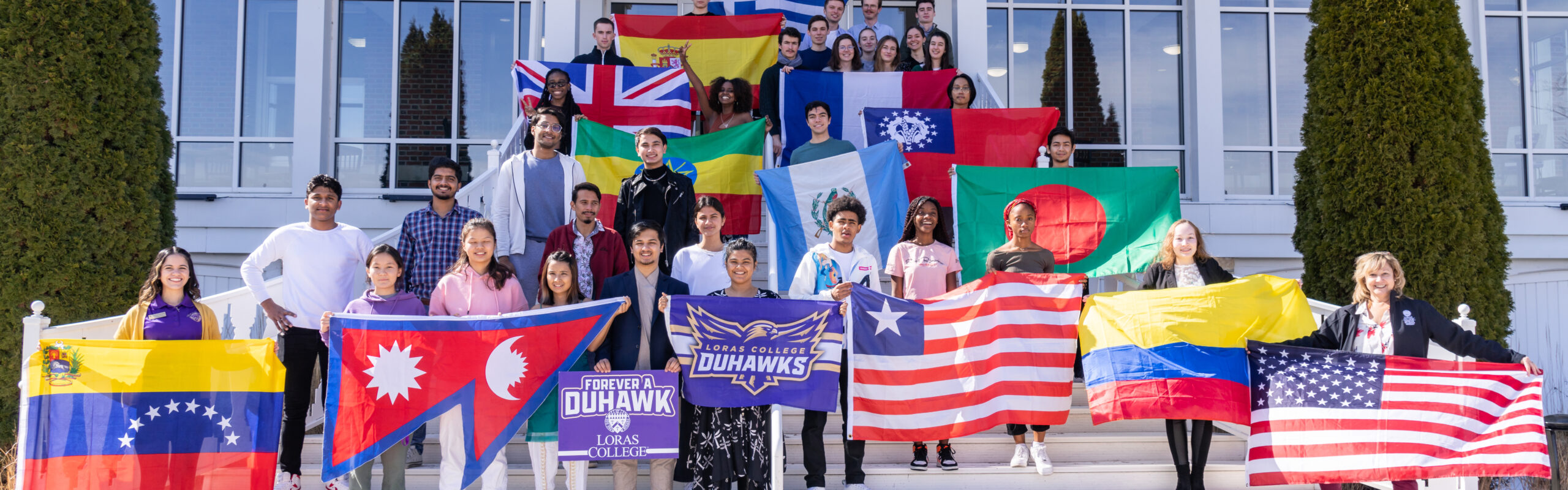 Loras International Students on Keane Hall porch holding their respective country flag