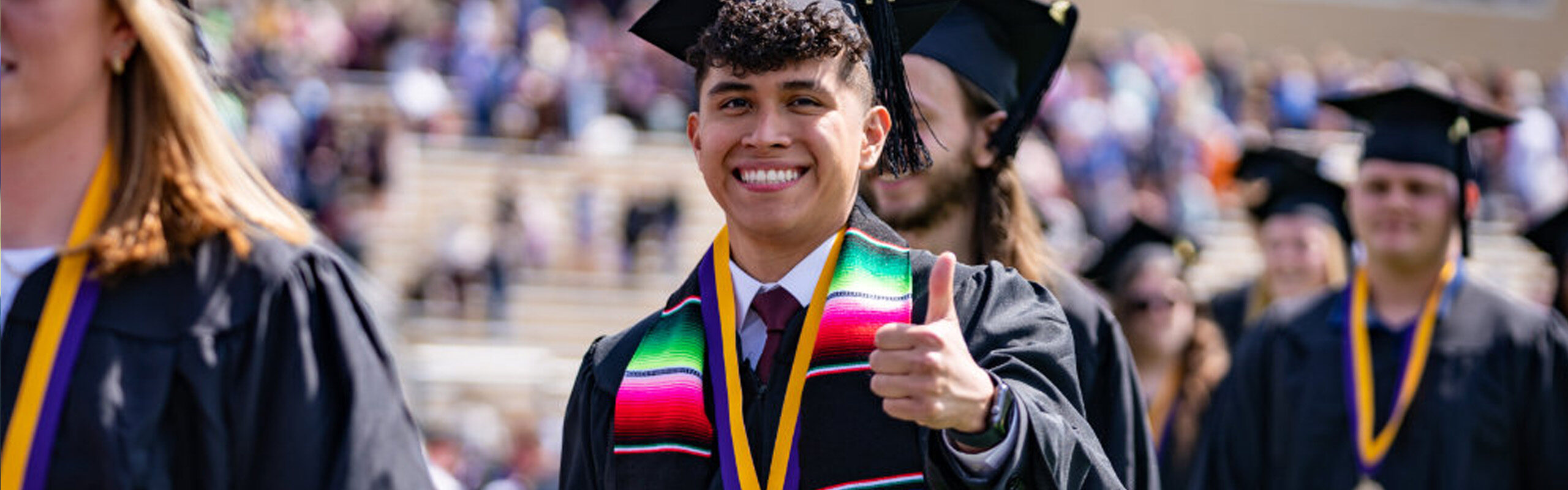 Loras male student showcasing international scarf during Commencement