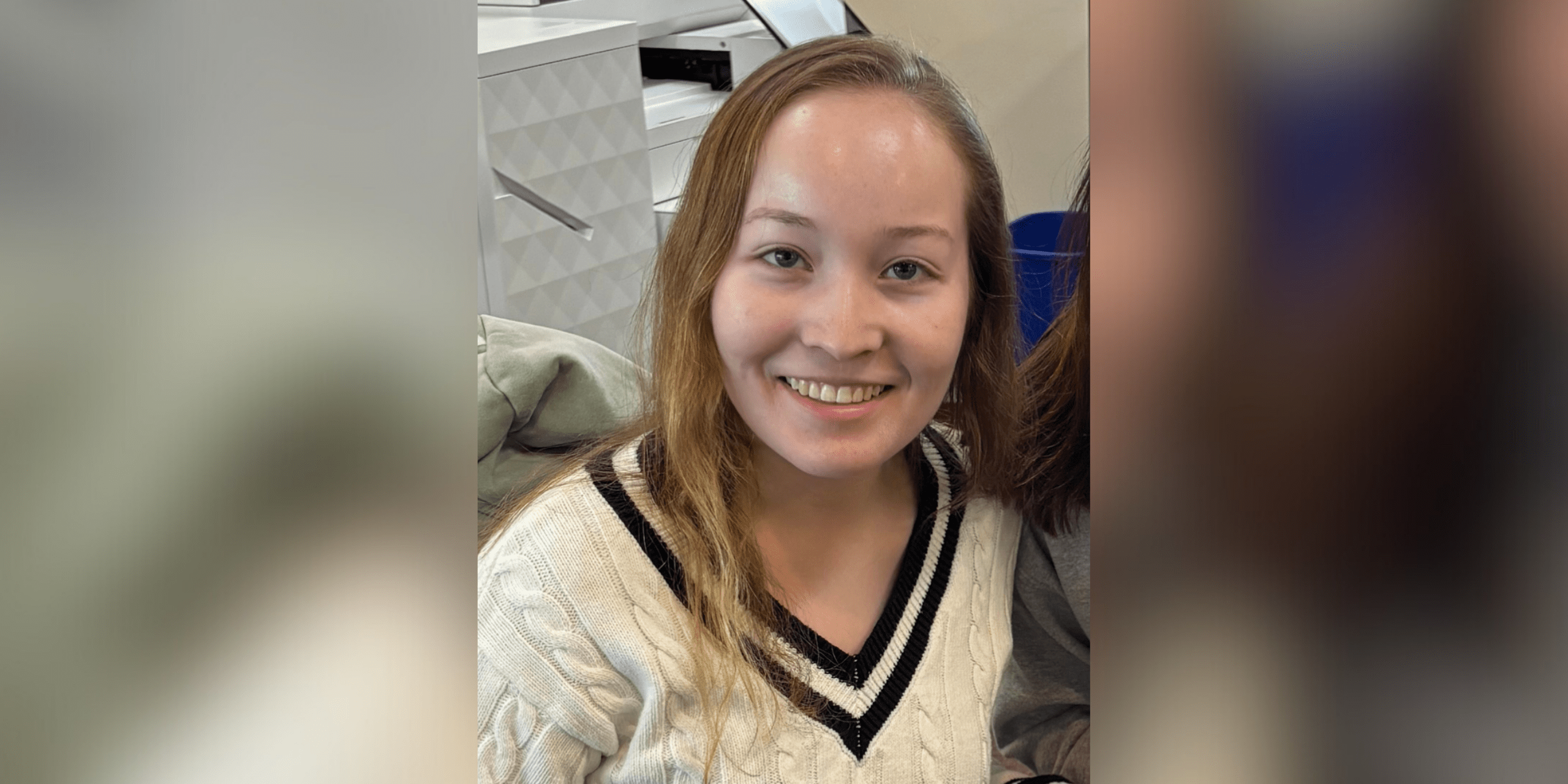 female student in sweater smiling at camera