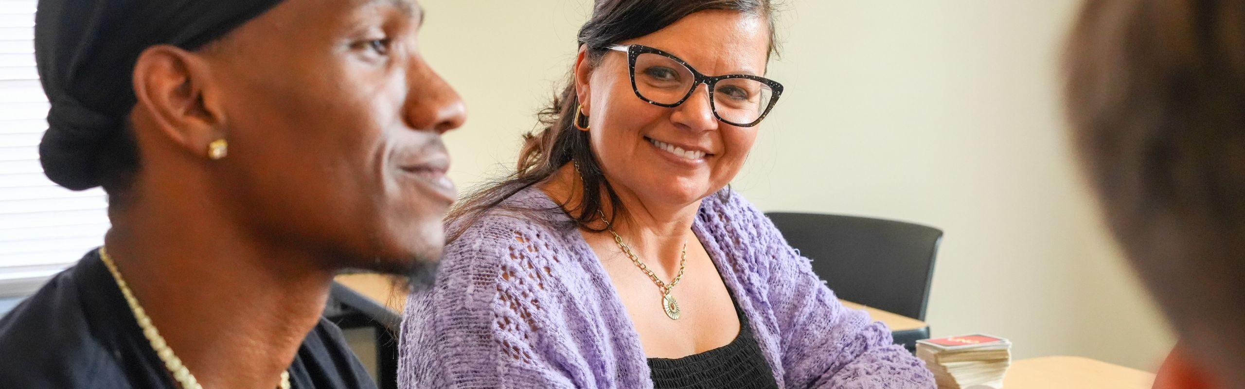 Professor in purple sweater observing student interactions