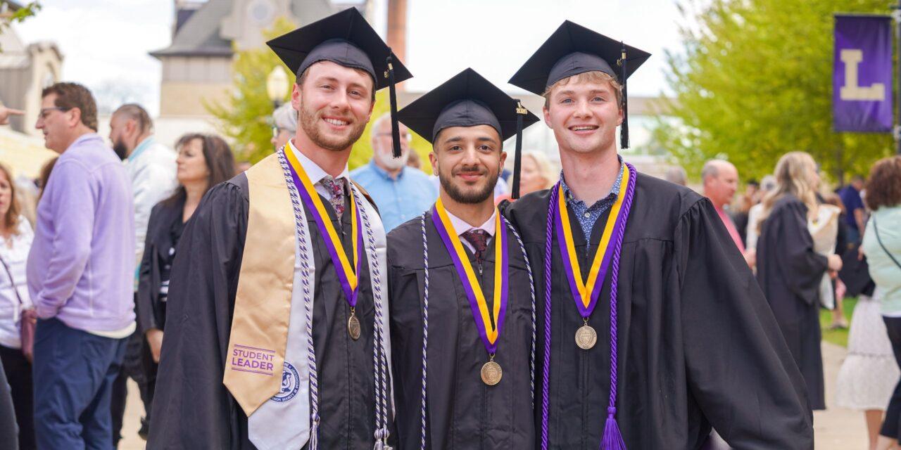 three graduates smiling in graduation hat and gown at Loras College