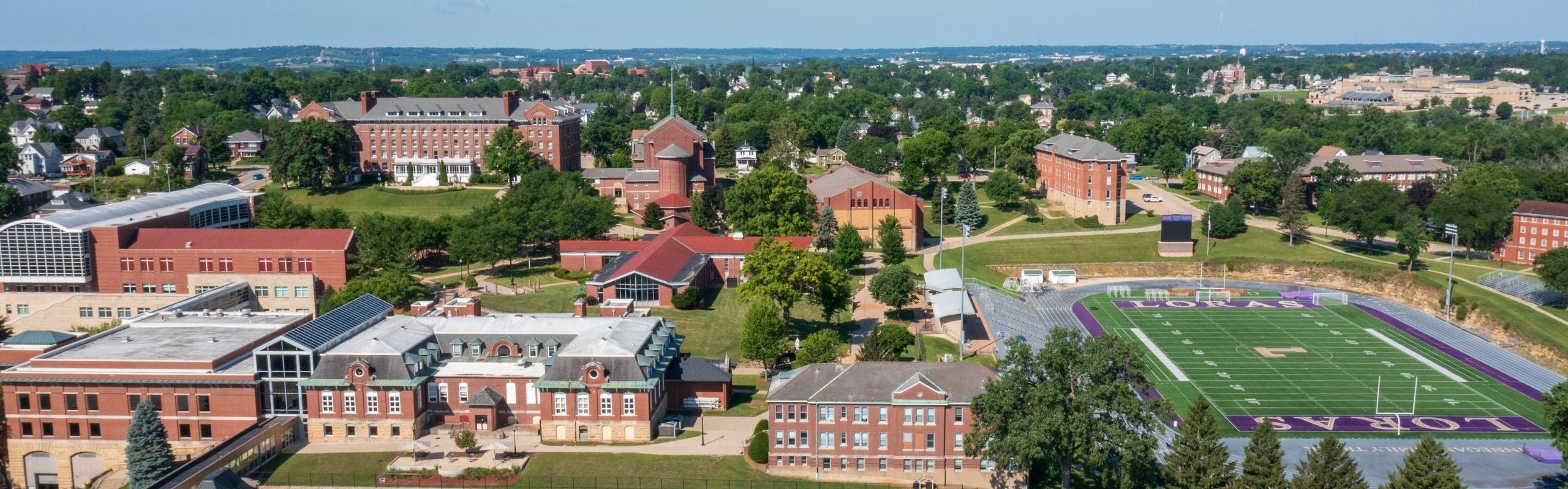 Aerial view looking up at Loras College campus with buildings and american football field.