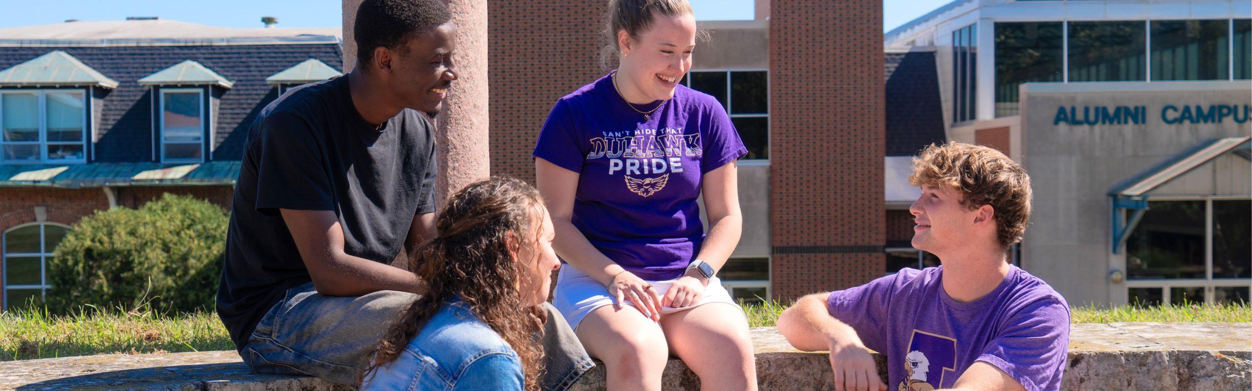 four people sitting and talking outside