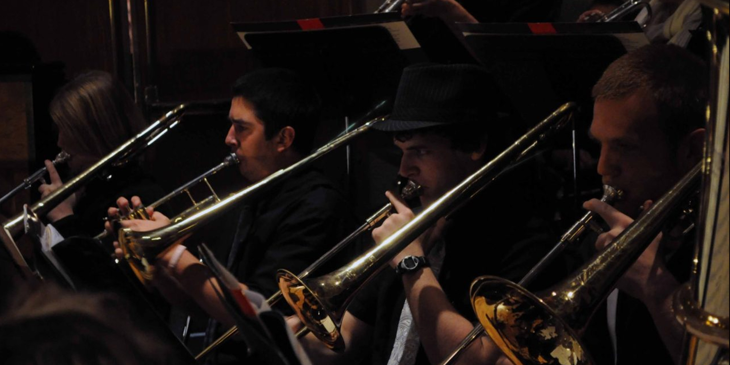 male trombone section reading music and playing