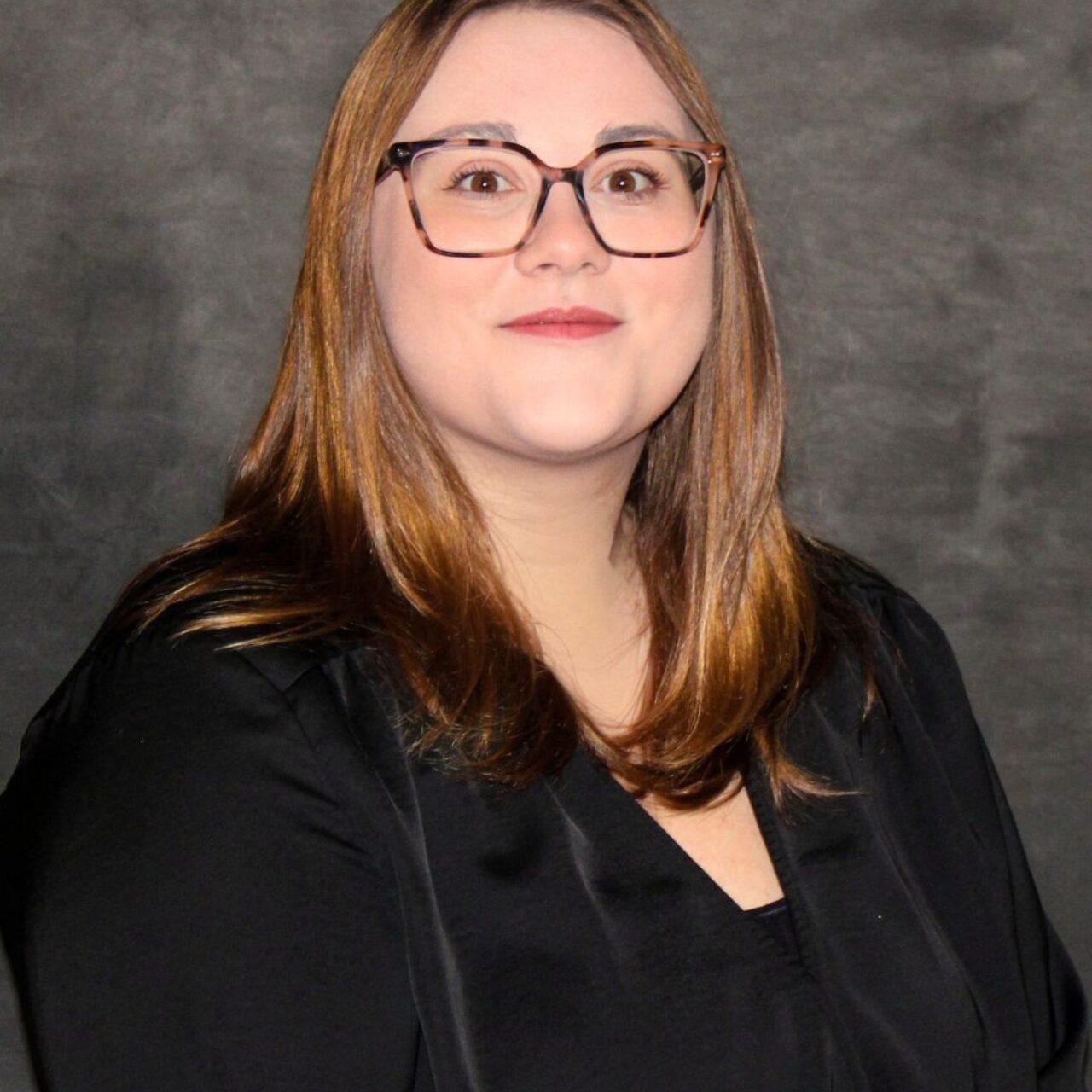 smiling Loras employee in black shirt with long hair and glasses