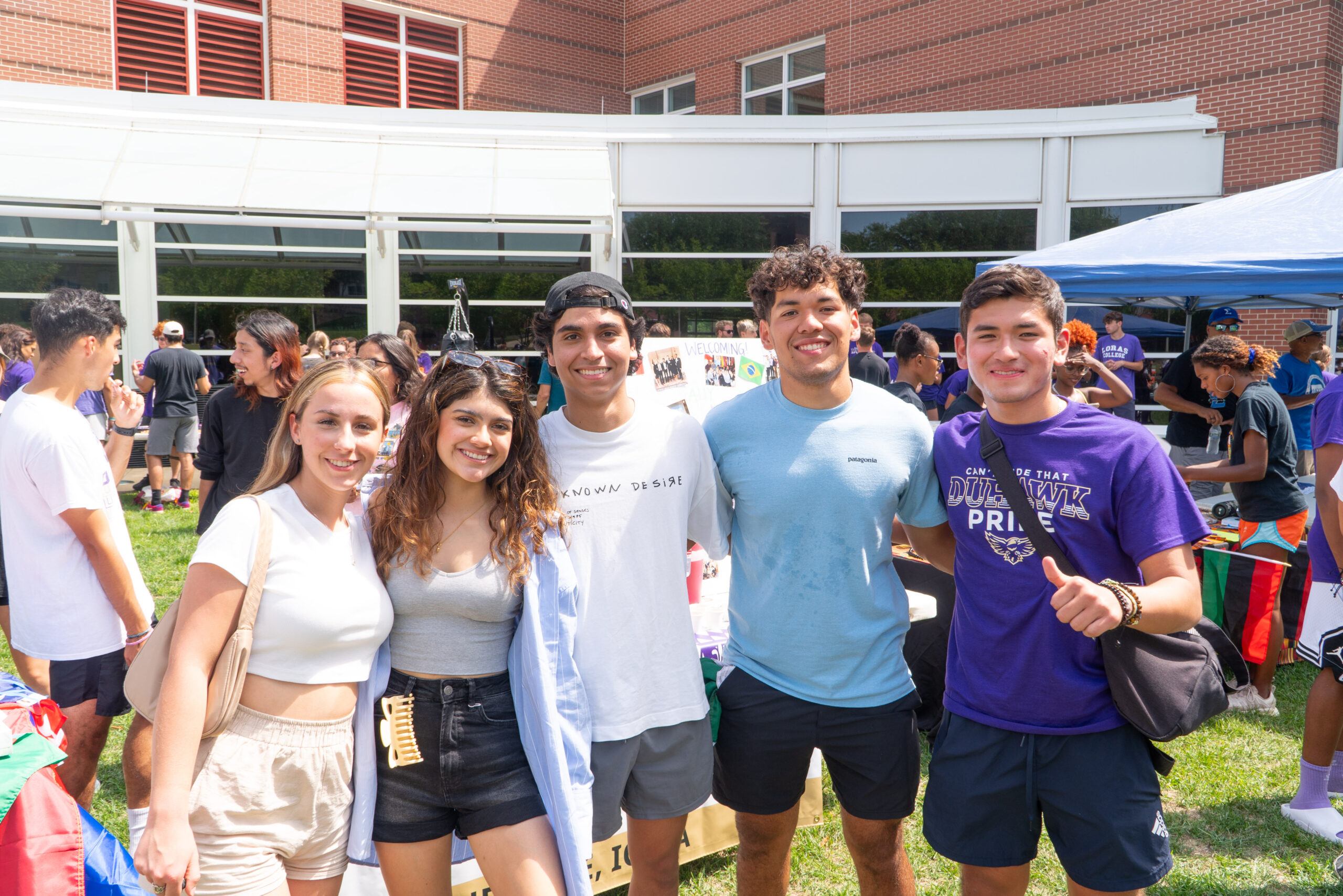 Six smiling Loras students standing in front of Campus Fest