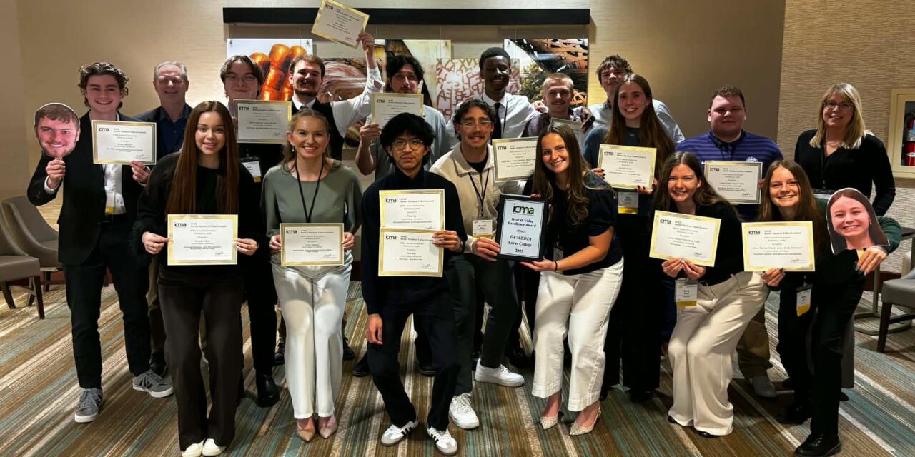 A group of Loras College Creative Media students and faculty stand together indoors holding ICMA award certificates and a plaque, smiling after winning multiple awards at the Iowa College Media Association Conference.