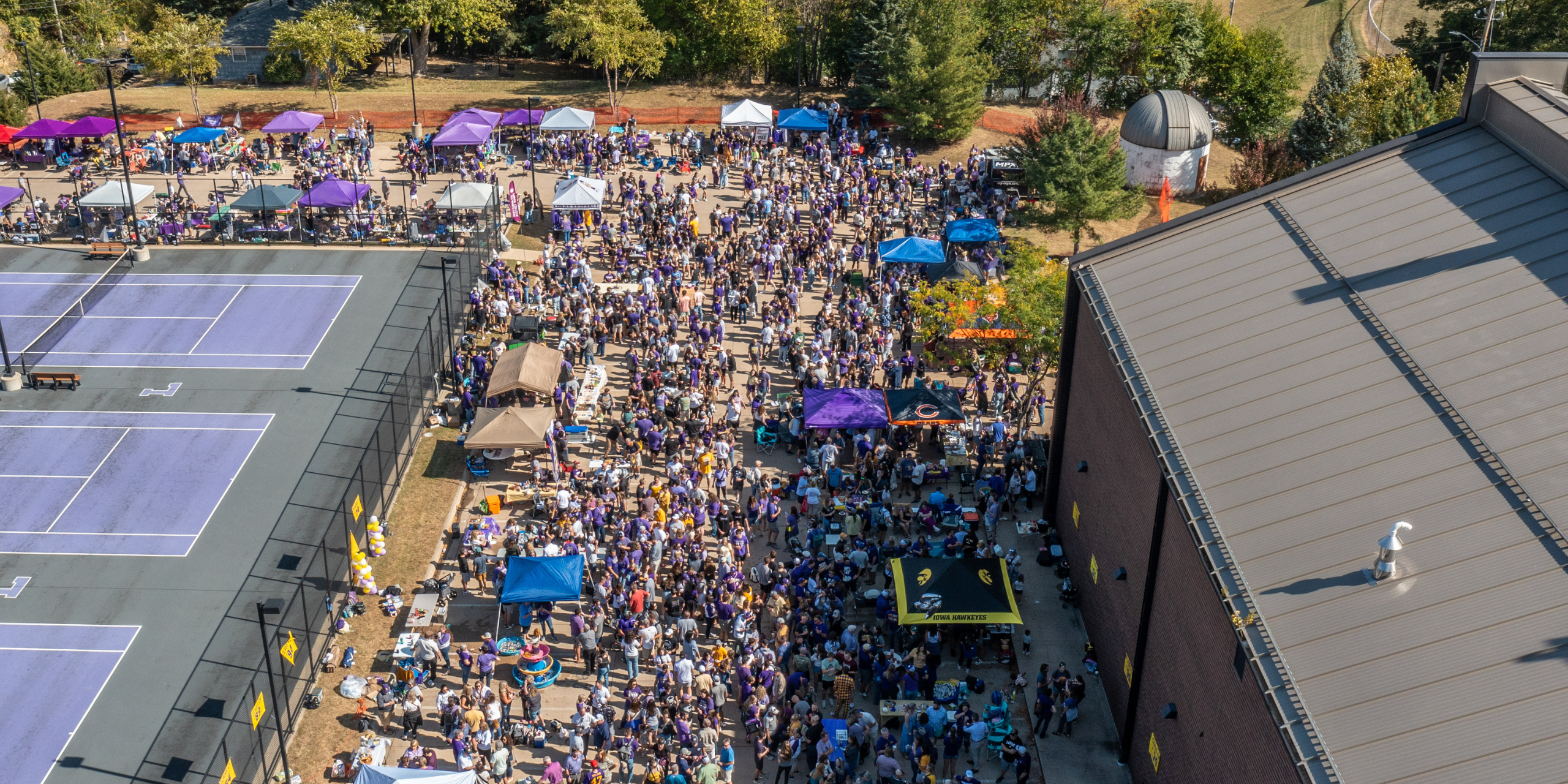 Large crowd of people in parking lot for Homecoming tailgate.