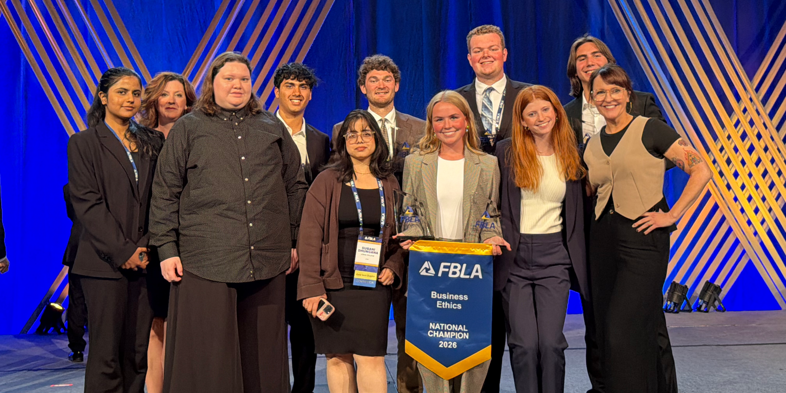 Loras College FBLA students and advisors gather on stage with awards and the 2026 Business Ethics National Champion banner following competition at the FBLA National Leadership Conference.